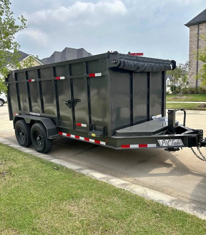 Fourteen-foot tandem-axle hydraulic dump trailer with tall steel sides and a rolled-up tarp, parked on a driveway