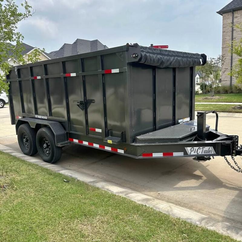 Fourteen-foot tandem-axle hydraulic dump trailer with tall steel sides and a rolled-up tarp, parked on a driveway